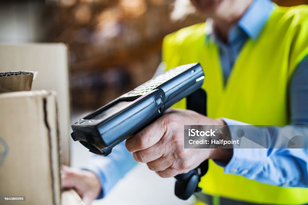 Warehouse woman worker with barcode scanner. Unrecognizable warehouse woman worker or supervisor using a mobile handheld PC with barcode scanner. Bar Code Reader Stock Photo