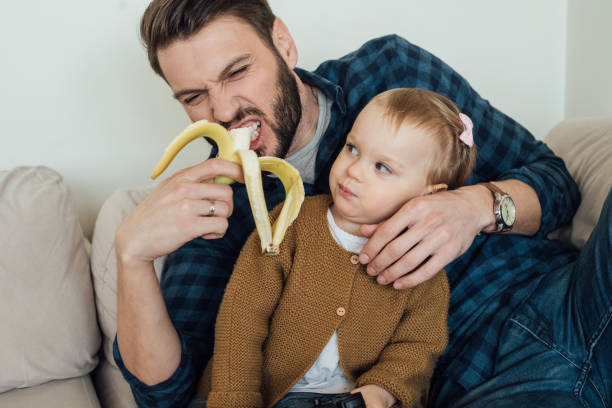 istock Father hugging daughter and eating banana 964384306