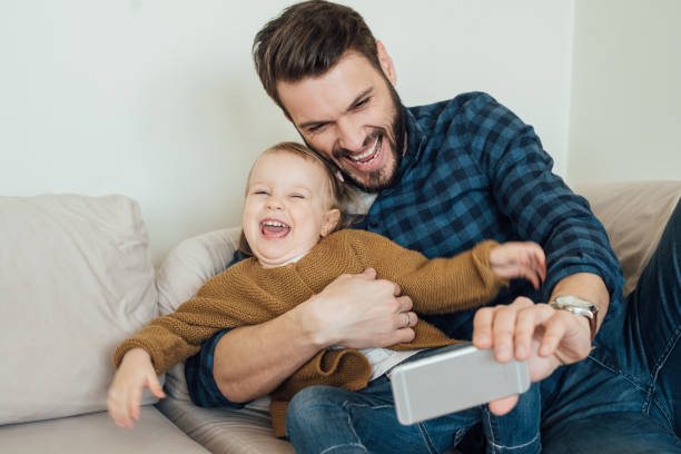 istock Father and daughter laughing and making selfie photographs 964384678