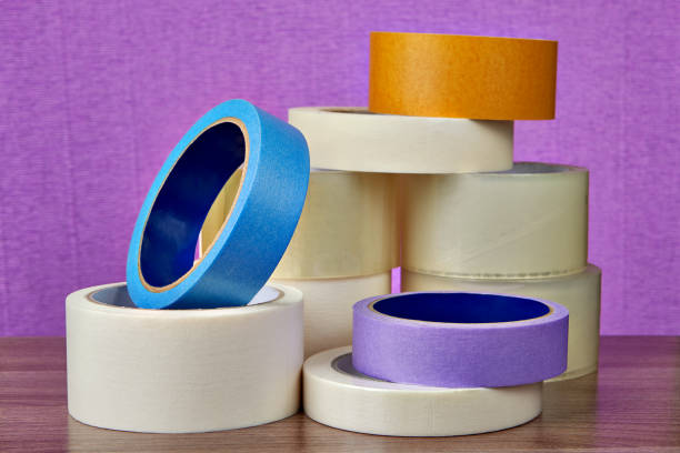 istock Heap of multicolor and multipurpose adhesive tape rolls, on purple. 964387382