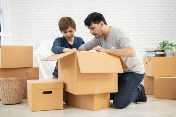 istock Couple unpacking cardboard boxes at new home. Moving house. 964399002