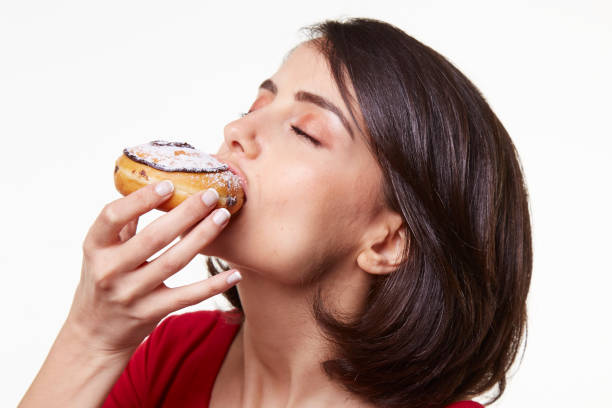 istock young woman eating a donut 964409150
