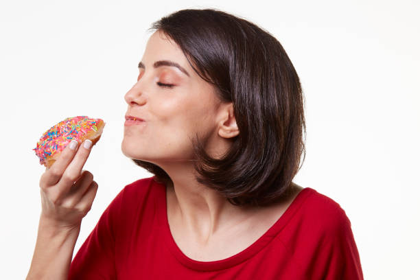 istock young woman eating a donut 964409260