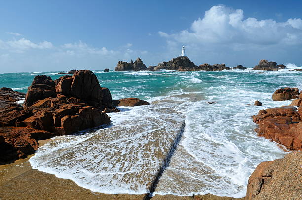 Corbiere Lighthouse, Jersey as seen from the rocky shore Wide angle shot of rushing tide on causeway with polarizer.Most southerly lighthouse in Great Britain. causeway photos stock pictures, royalty-free photos & images