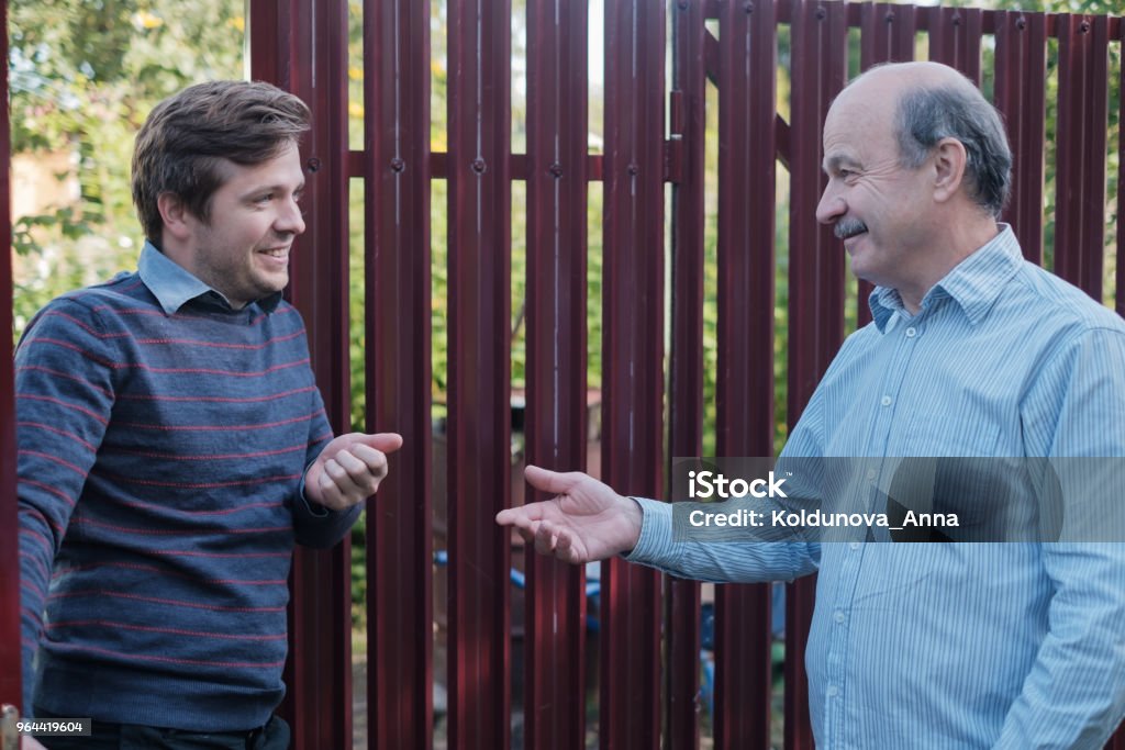 two farmers takling to each other on sunny day. They discuss important news two friends and neighbors takling to each other on sunny day. They discuss important news Neighbor Stock Photo