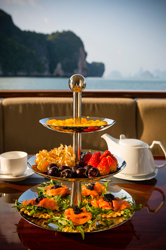 Afternoon tea with a three tiered snack server on a luxury motor yacht in Phang Nga Bay near Phuket, Thailand.