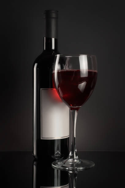 istock Red wine bottle and full wineglass on black 964428446