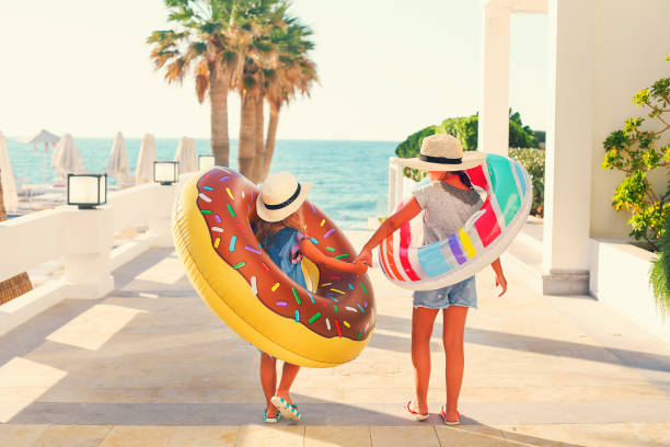 deux petites filles avec des jouets gonflables sur la plage - summer sport equipment inflatable photos et images de collection