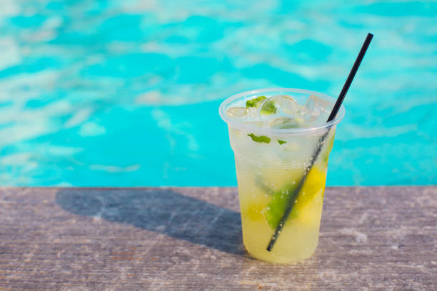 istock Cocktail glass on turquiose water background 964429342