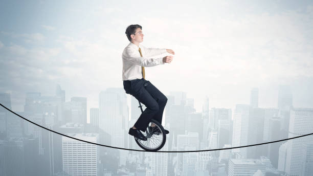 istock Brave guy riding a monocycle on a rope above cityscape 964432020