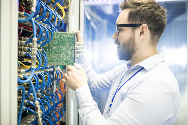 istock Serious sophisticated IT engineer in glasses viewing hardware equipment of supercomputer and examining network switch in server room 964442172