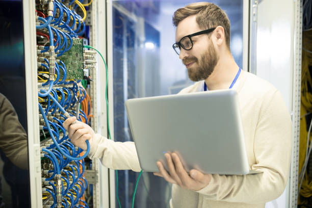 istock Content confident handsome male IT engineer in glasses checking cables of supercomputer while working on productivity of network server 964442358