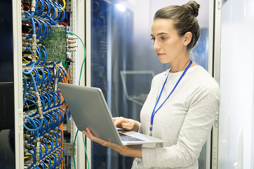 Confident female IT engineer checking internet access in server room