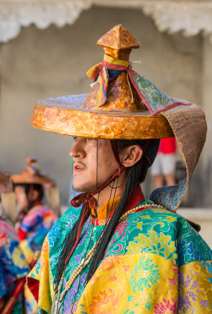 Buddhist monk in traditonal costume during monastery festival Phyang, India - July 14, 2015: Buddhist monk in traditonal costume during monastery festival while he is watching and listening to traditional music during in a festival in the courtyard of Phyang Monastery, Ladakh. phyang monastery stock pictures, royalty-free photos & images