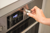 Close up of women hand setting cooking mode or temperature on oven