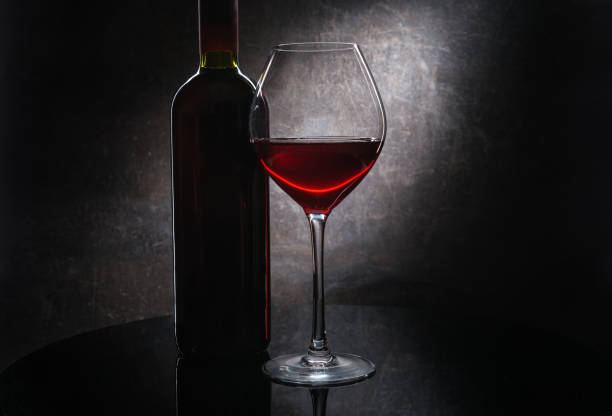 istock Red wine glass and bottle on dark background 964454740