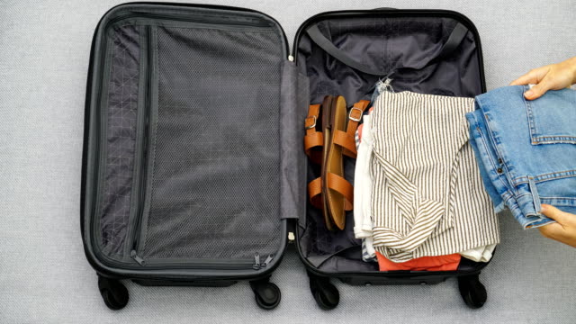 4K stop motion animation of female hands packing clothes into a suitcase