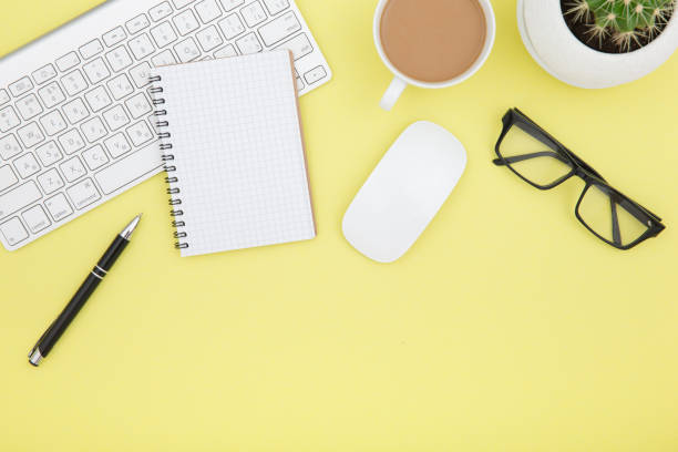 istock workspace with tablet, keyboard, coffee cup and eyeglasses copy space on yelow background. Top view. 964484080