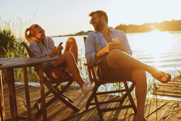 istock Young woman and man using smartphone by the river 964487612