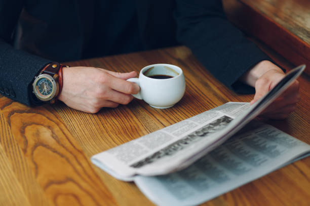 istock Man's hands close-up holding cup of coffee and a newspaper 964487862