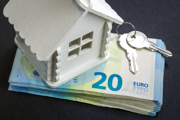istock Miniature house, a bundle of money and keys are on a black surface 964500570