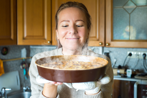 Young woman holding a baking tray with a ready cake