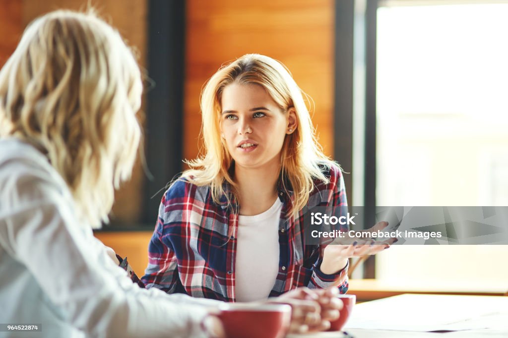 カフェでコーヒーを飲みながらおしゃべり 2 つの若い女友達。金髪の女性が問題を議論します。 - 話すのロイヤリティフリーストックフォト
