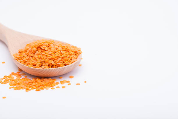 istock Red lentils in wooden spoon on white background 964527594