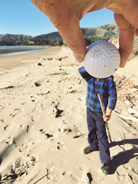 boy with golf ball obscuring face - golf child sport humor imagens e fotografias de stock