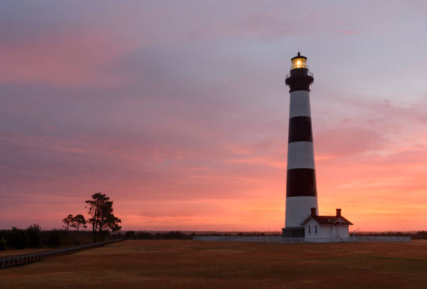Bodie Lighthouse at Sunrise - North Carolina Bodie lighthouse in Cape Hatteras National Seashore along Atlantic coast of North Carolina.   Colorful sky at dawn with colors of pink and orange. bodie island stock pictures, royalty-free photos & images