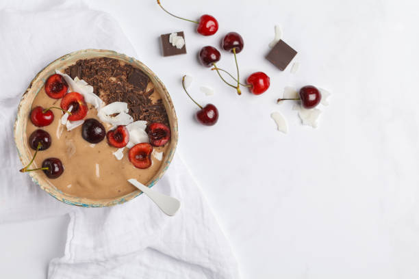 istock Chocolate - cherry smoothie bowl with coconut and bananas on white background, top view, copy space. Healthy vegan food concept. 964564406