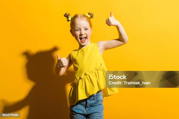 Girl With Red Hair On A Yellow Background The Girl Laughs And Shows The Class Sign Stock Photo - Download Image Now