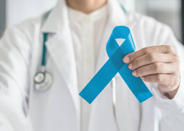 nastro blu simbolico per la campagna di sensibilizzazione sul cancro alla prostata e la salute degli uomini in mano al medico - horizontal ribbon image descriptive color foto e immagini stock