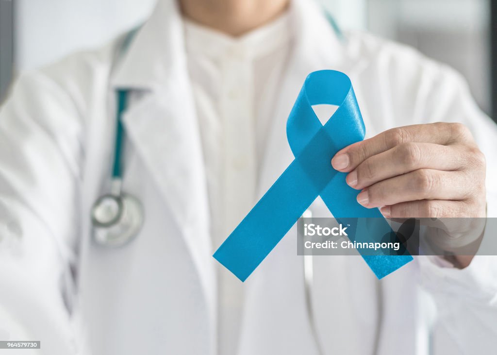 Fita azul simbólica para a campanha de conscientização do câncer de próstata e a saúde dos homens na mão do médico - Foto de stock de Câncer de próstata royalty-free