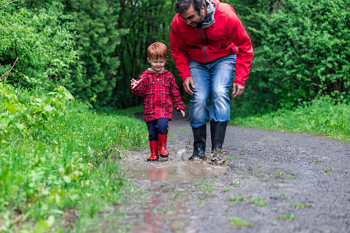 Young Cute Kid Walking Jumping into Water Puddle with Dad