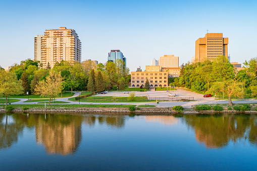 Skyline stock photograph of downtown London Ontario Canada with waterfront park and the Thames River during sunset. Day and Night Series