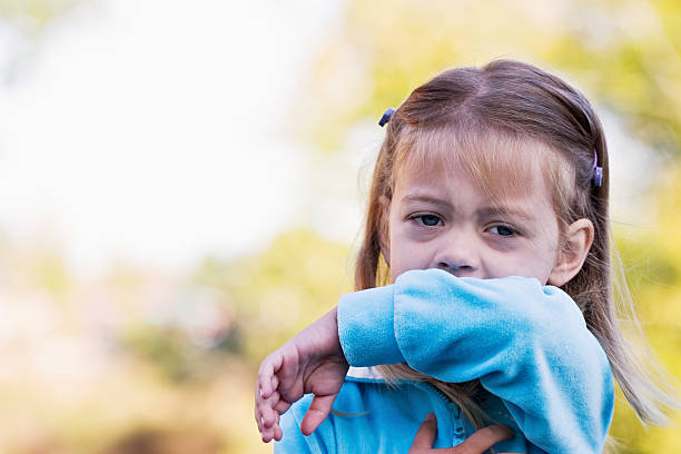 A little girl sneezing in to get elbow
