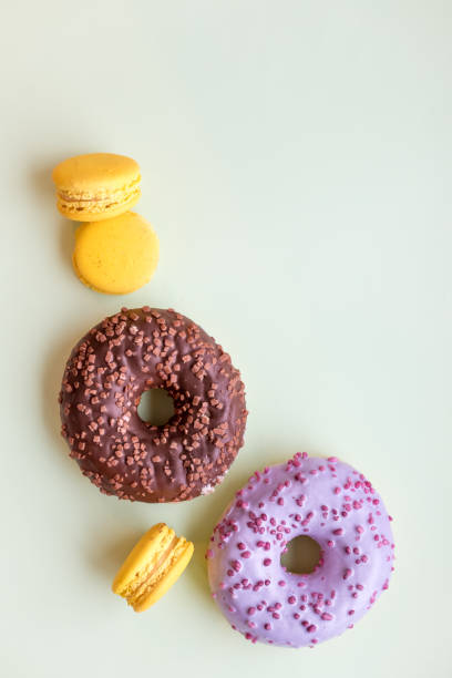 istock Glazed donuts and macaroons. Sweet dessert isolated on soft green background. Cakes with buttercream. lemon, yellow macaron cookies.Pop art color style.Selective focus. Copy space 964659524