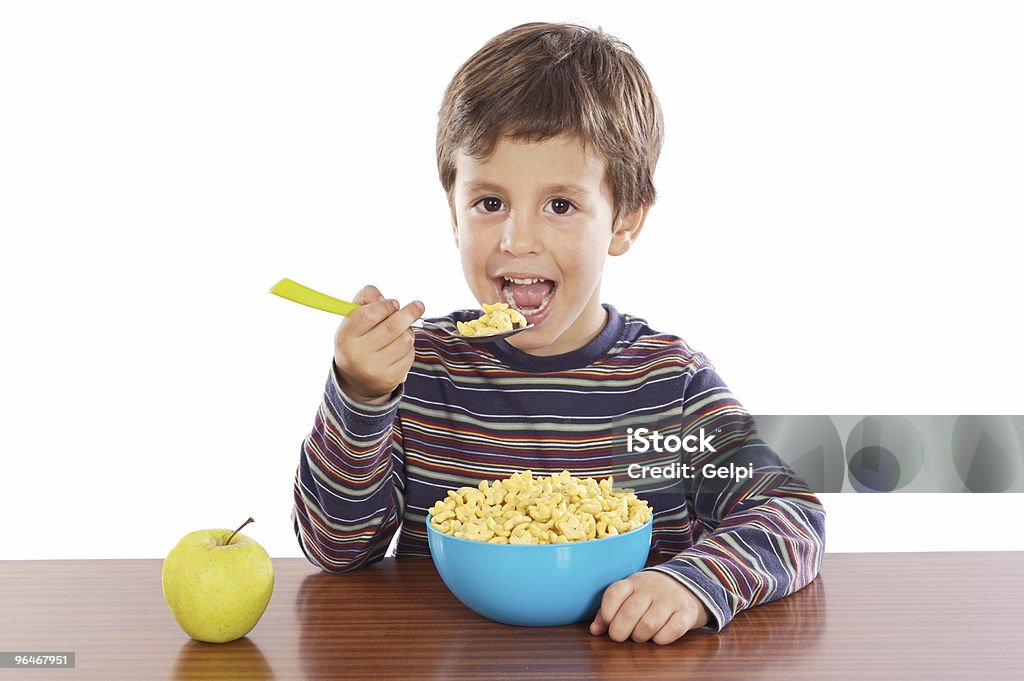 Young child eating a massive bowl of breakfast cereal Child eating breakfast a over white background Apple - Fruit Stock Photo