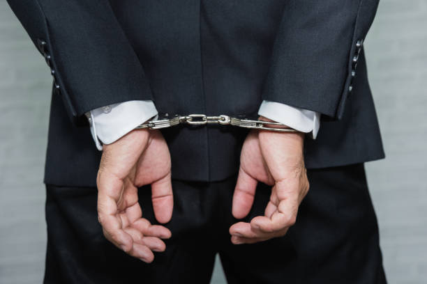 istock Arrested businessman in handcuffs with hands behind back 964700848