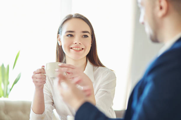 istock Smiling young businesswoman having friendly talk with unrecognizable business partner during coffee meeting 964700882