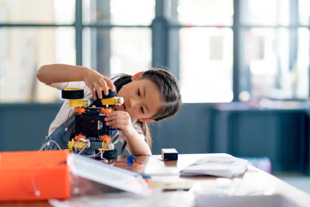 Photo of Young girl working on a robot design