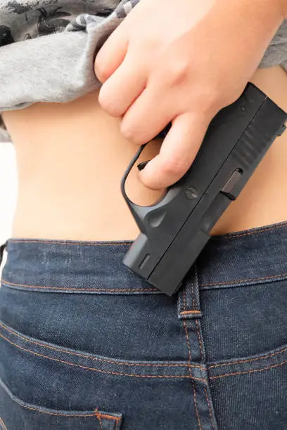 Gun put of jeans at the young woman