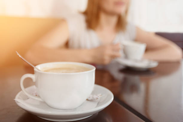 istock Selective focus on a cup with aromatic coffee. Blurred background with girl drinking coffee cup 964722970