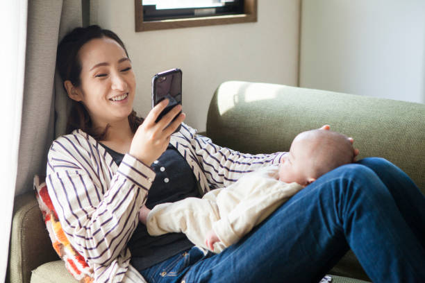 istock A mother holding a baby and doing a mobile operation. 964736914