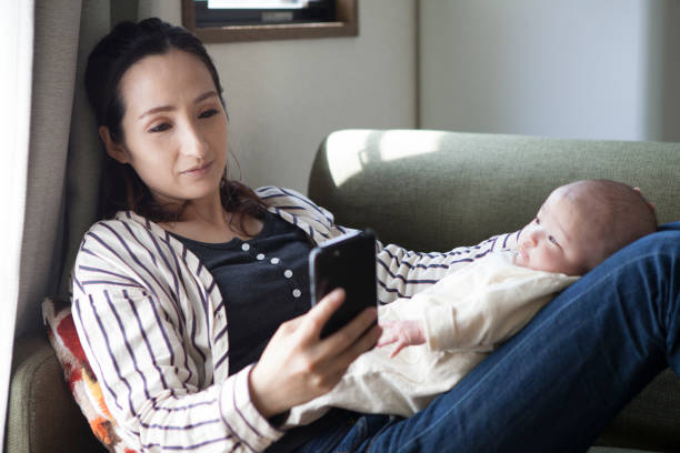 istock A mother holding a baby and doing a mobile operation. 964736938