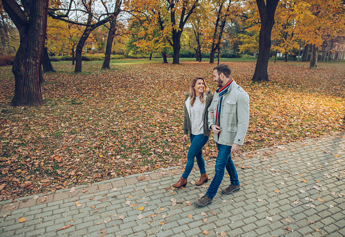 Young happy couple communicating while taking an autumn walk in the park.