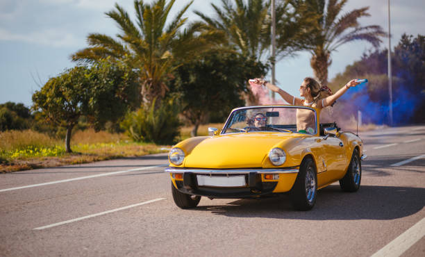 istock Young women having fun with smoke bombs in convertible car 964754720