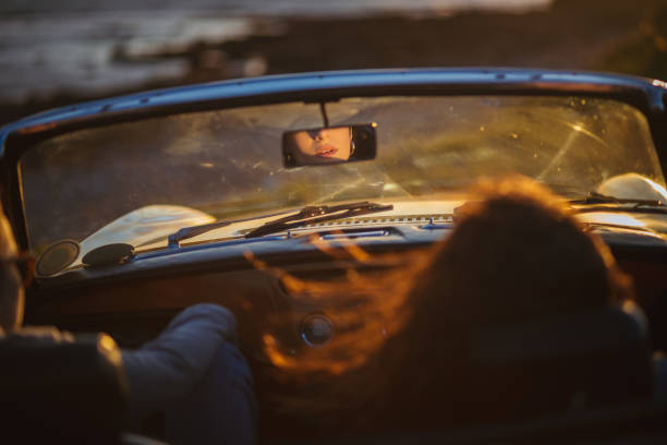 Rear view mirror reflection of woman's lips in cabriolet car