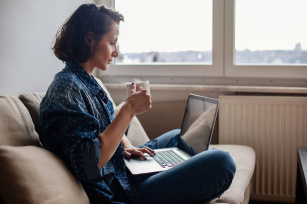 istock Woman using laptop on sofa and drinking coffee 964761958